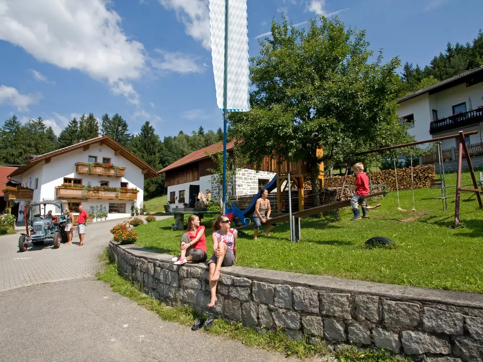 ein Hofgelände mit Ferienhaus, Stallgebäude  und Wohnhaus, Spielplatz und Traktor  