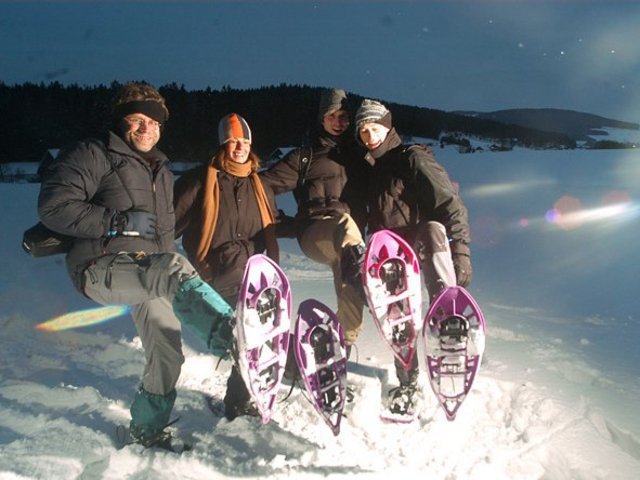 Gruppe von Schneeschuhwanderer mit Stirnlampen unterwegs durch die nächtliche Schneelandschaft 