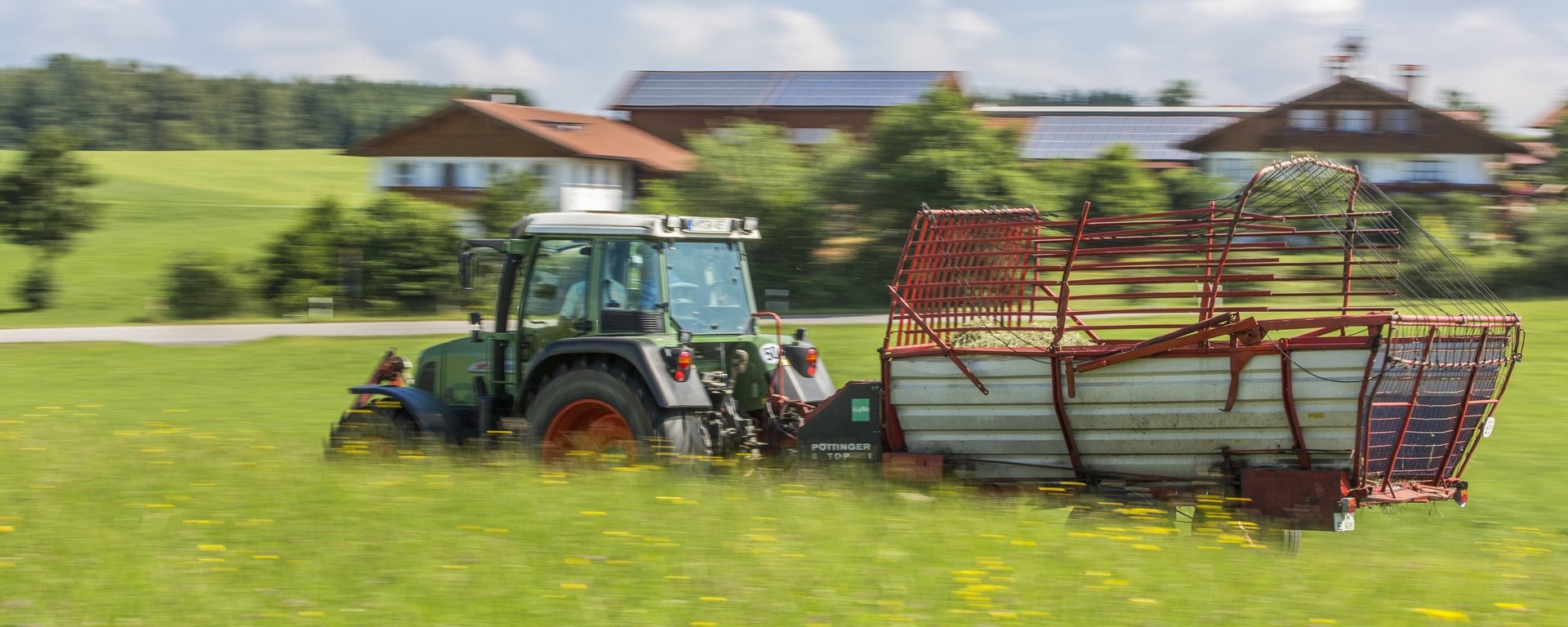 Traktro mit Ladewagen auf der Wiese 