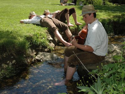 drei junge Trachtler genießen den kühlende Bach, mit musikalischer Begleitung   